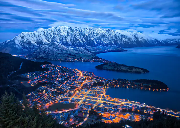 城市夜晚的山景湖光 4K高清晰度壁纸，呈现雪覆盖的山峰与璀璨的城市灯光